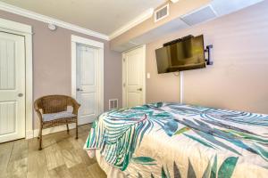 a bedroom with a bed and a tv on the wall at Beach House Condominiums B101 - Beachfront with Pool, WiFi, & Beach Service in Destin