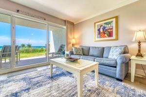 a living room with a couch and a table at Beach House Condominiums B101 - Beachfront with Pool, WiFi, & Beach Service in Destin