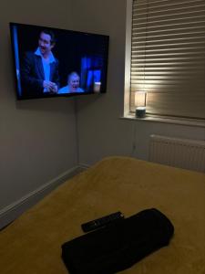 a television in a bedroom with a remote control on a bed at The retreat in Nottingham