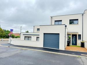 a white building with a large garage door at Maison 8 couchages Parking Extérieur,Climatisation -Mesange in Aubière