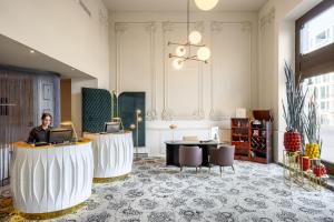 a woman sitting at a desk in a lobby at Nemzeti Hotel Budapest - MGallery Collection in Budapest