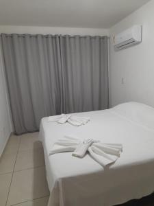 Una cama blanca con dos toallas blancas encima. en Le Bon Vivant 307 B, en Arraial do Cabo