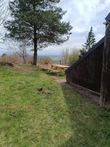 a picnic table next to a fence and a tree at Charmant Chalet de montagne in Picherande