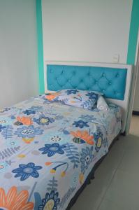 a bed with a blue head board with a floral bedspread at SANDY APARTAMENTO in Santa Rosa de Cabal +15 photos