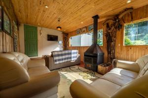 a living room with leather couches and a stove at Pousada Morro Grande in Bom Jardim da Serra