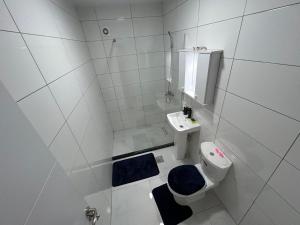 a white bathroom with a toilet and a sink at Skenderaj Center Apartment in Mitrovica