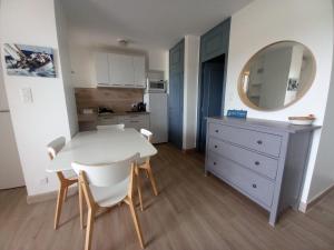 Una cocina y un comedor con una mesa y sillas blancas. en Marines de Cogolin, studio neuf face à la plage, climatisation, wifi, terrasse, proche St Tropez, en Cogolin