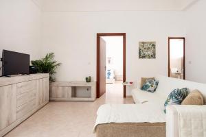 a white living room with a white couch and a tv at Chez Dione in Siracusa