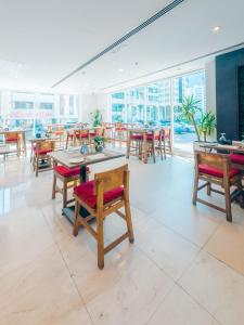 a dining room with tables and chairs and windows at Kingsgate Hotel by Millennium in Abu Dhabi