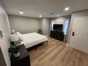 ein Schlafzimmer mit einem weißen Bett und einem Fernseher in der Unterkunft Aksarben Area 2 BD-2 BA by UNO in Omaha