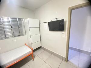 a small room with a bench and a tv at Hostel Gravatá in Piracicaba