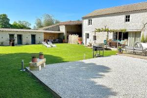 une arrière-cour d'une maison avec une pelouse et un grill dans l'établissement La Grange - Gîte de Prestige La Rochelle, à Saint-Médard-dʼAunis