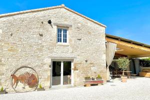 Cette maison en pierre dispose d'une grande fenêtre et d'une terrasse. dans l'établissement La Grange - Gîte de Prestige La Rochelle, à Saint-Médard-dʼAunis