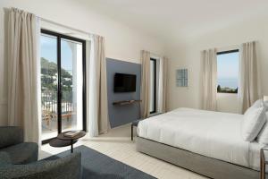 a bedroom with a white bed and a large window at Villa Certosa Boutique Hotel Capri in Capri