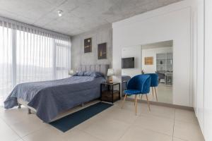ein Schlafzimmer mit einem Bett und einem blauen Stuhl in der Unterkunft Skyline iFreses, 22nd floor! AC, TV and Pool in Guayabos
