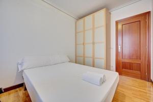 una camera da letto con un letto bianco e una porta di legno di La Piscina de Cascajos by Clabao a Logroño Altre 28 foto