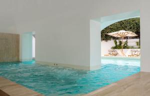 a swimming pool with an umbrella and blue water at Villa Certosa Boutique Hotel Capri in Capri