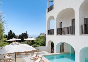 a house with a swimming pool and a patio with umbrellas at Villa Certosa Boutique Hotel Capri in Capri