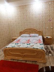 a bedroom with a wooden bed with flowers on it at VIP 2 Квартира-студия 1ком in Uralsk +2 photos