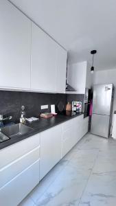 eine weiße Küche mit Spüle und Kühlschrank in der Unterkunft Boulogne, Near Roland Garros in Boulogne-Billancourt + 14 Fotos
