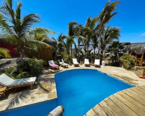 a swimming pool with lounge chairs and palm trees at El Mirador de Vichayito in Vichayito