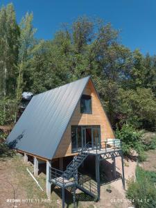 a tiny house with a metal roof and a porch at Riverside Guest house Mashkhur in Arslanbob