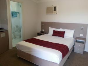 a bedroom with a large bed with a red pillow at Bargo Motor Inn in Bargo