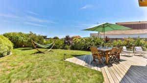 a patio with a table and a green umbrella at Villa des Loups de Mer in Talmont
