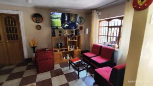 ein Wohnzimmer mit rosa Stühlen und einem Flachbild-TV in der Unterkunft Casa El Capulí in Cajamarca