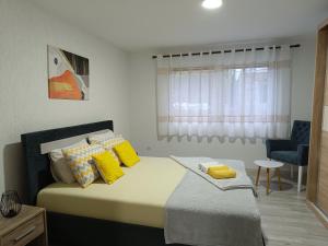 a bedroom with a bed with yellow pillows and a window at Apartman D in Višegrad