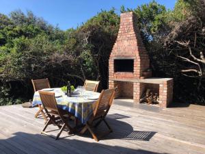 un tavolo e delle sedie su un ponte con un camino in mattoni di Seals Cottage Excellent Main Beach Access a Cape St Francis Altre 15 foto