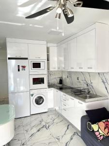 a kitchen with white cabinets and a washer and dryer at Río Canario 102 in Mogán