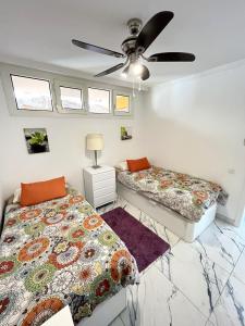 a bedroom with two beds and a ceiling fan at Río Canario 102 in Mogán