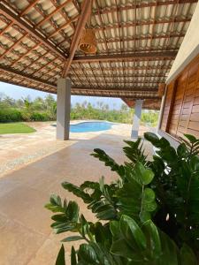 an outdoor patio with awning and a swimming pool at Mansão Guajiru Suítes in Guajiru