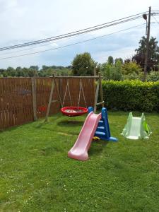 three childrens play equipment in a yard at Le petit nid in Brugelette