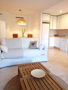 ein Wohnzimmer mit einer weißen Couch und einem Tisch in der Unterkunft COSTA GALERA Apartamento con piscinas jardín y un baño cercano a la playa in Estepona