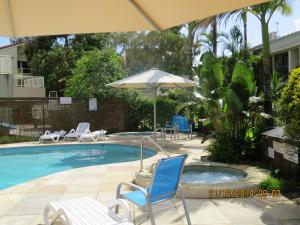 - une piscine avec des chaises et un parasol dans l'établissement Noosa Keys Resort, à Noosaville