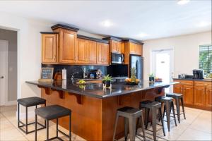 フォート・ローダーデールにあるHeated Saltwater Pool 6min to Beach Tropical Oasisのキッチン(木製キャビネット、バースツール付)