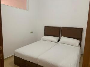 a bed with two white pillows in a room at شقة مفروشة in Beni Enzar