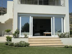 a white house with large sliding glass doors at Villa with Aegean views in Akhladherí
