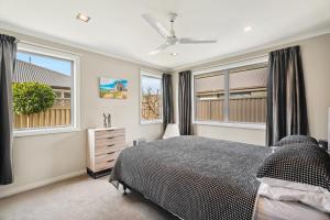 a bedroom with a bed and two windows at Beauty on Bantry - Alexandra Holiday Home in Alexandra
