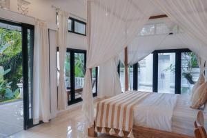 a bedroom with a bed with curtains and windows at J4 Villa Ubud in Ubud