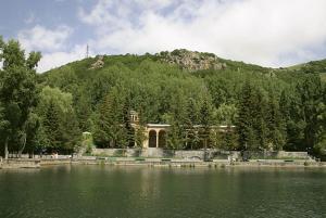 a building next to a lake with a mountain at Jermuk Apartment in Jermuk