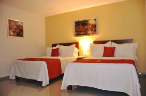 a hotel room with two beds with red and white sheets at Yakar in Córdoba