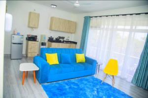 a living room with a blue couch and yellow pillows at Kezmo Paradise in Mombasa