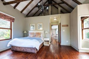 a bedroom with a large bed and wooden floors at Hogsback Arminel Self catering Cottages in Hogsback +49 photos