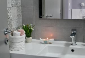 un lavandino in bagno con una candela e asciugamani di Leonardo Suites Scilla a Scilla