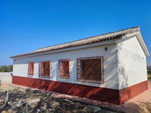 a small white building with red barred windows at Casa la Poveda in Villa del Prado