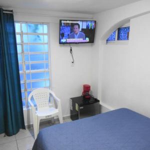 Un dormitorio con una cama y un televisor en la pared. en Cocos, en Cancún