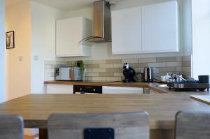 a kitchen with white cabinets and a wooden table at Church Street Studio Apartment in Keighley +18 photos